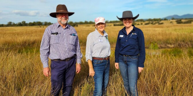Three FBA staff members standing in a field smiling at hte camera.