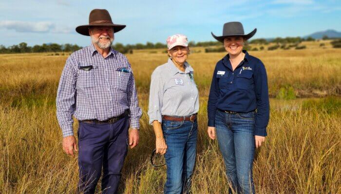 Three FBA staff members standing in a field smiling at hte camera.